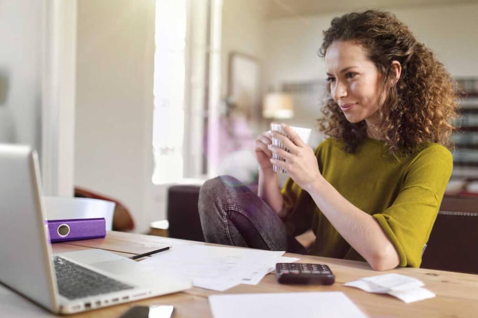 Zufriedene Kunden: Mit einem Serviceteam, das sich wirklich kümmert junge Frau sitzt mit Taschenrechner und Laptop am Tisch und ist zufriedenen mit dem Service ihres Stromanbieters lekker Energie